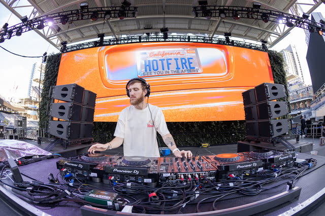 HOTFIRE behind four CDJs on a main stage, HOTFIRE across the LED wall behind him
