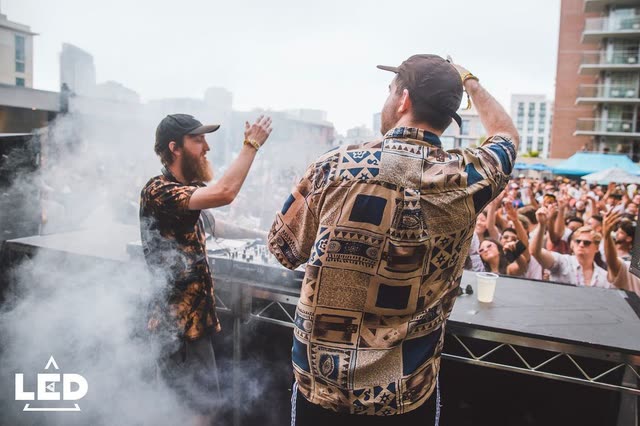 Daytime rooftop set with a crowd along the barricade